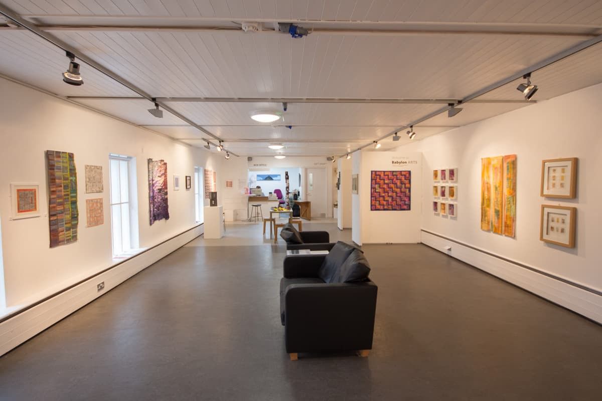 Things to do in East Cambridgeshire - Culture. Image of exterior of Babylon Gallery with tapestries on wall and armchairs