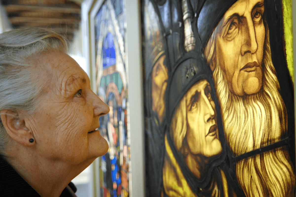 Things to do in East Cambridgeshire - Stained Glass Museum - Close up of older woman gazing at an intricate piece of stained glass